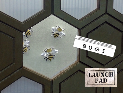 A wooden BEEHIVE wall greets visitors to the Kidzu Launch Pad. Sections of its honeycomb pattern open to reveal many surprises!