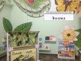 A cozy BOOK NOOK is decorated with art by textile artist Elaine O’Neal and butterfly puppets by Paperhand Puppet Intervention.