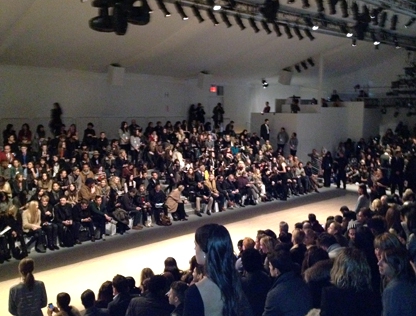 As spectators take their seats, the lights come up on the runway